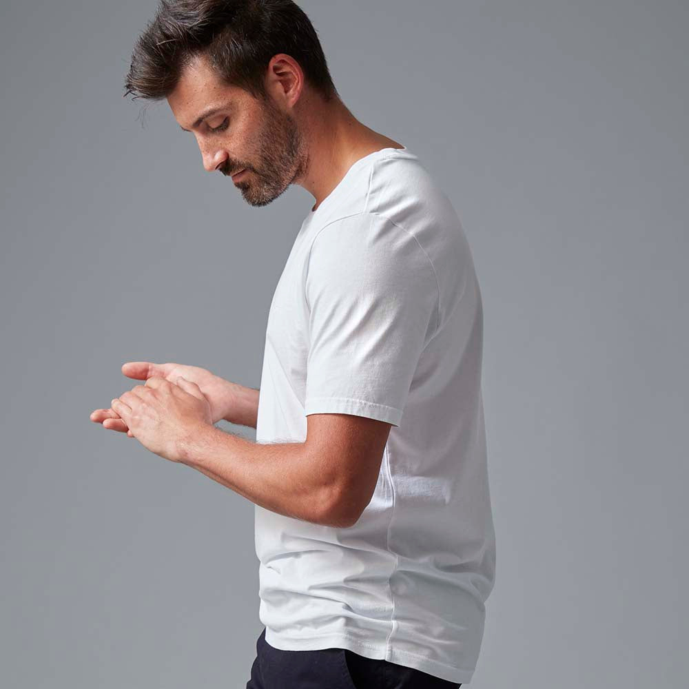 Man with brown hair and facial hair wearing a white tee.