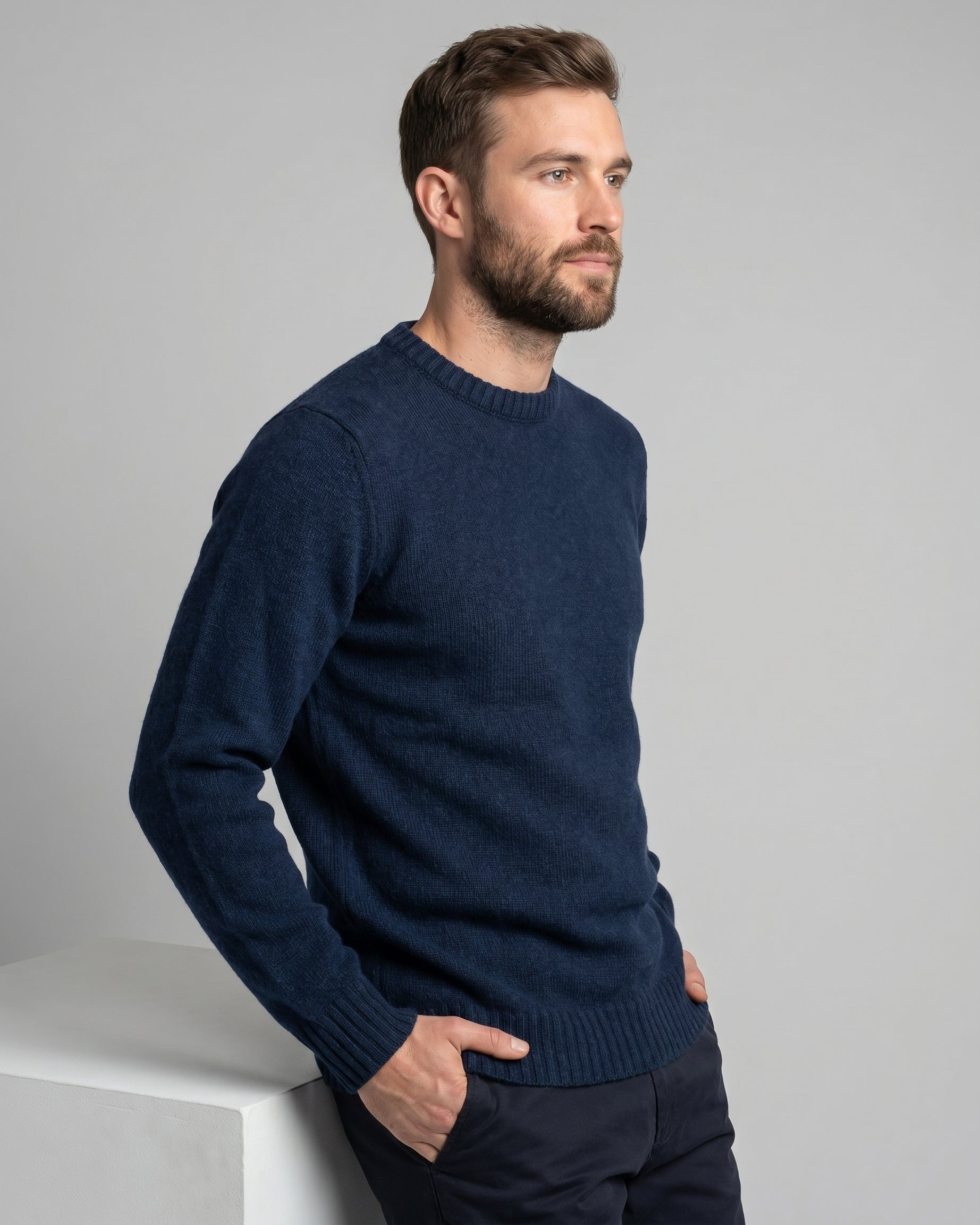 Man wearing a navy blue sweater against a gray background