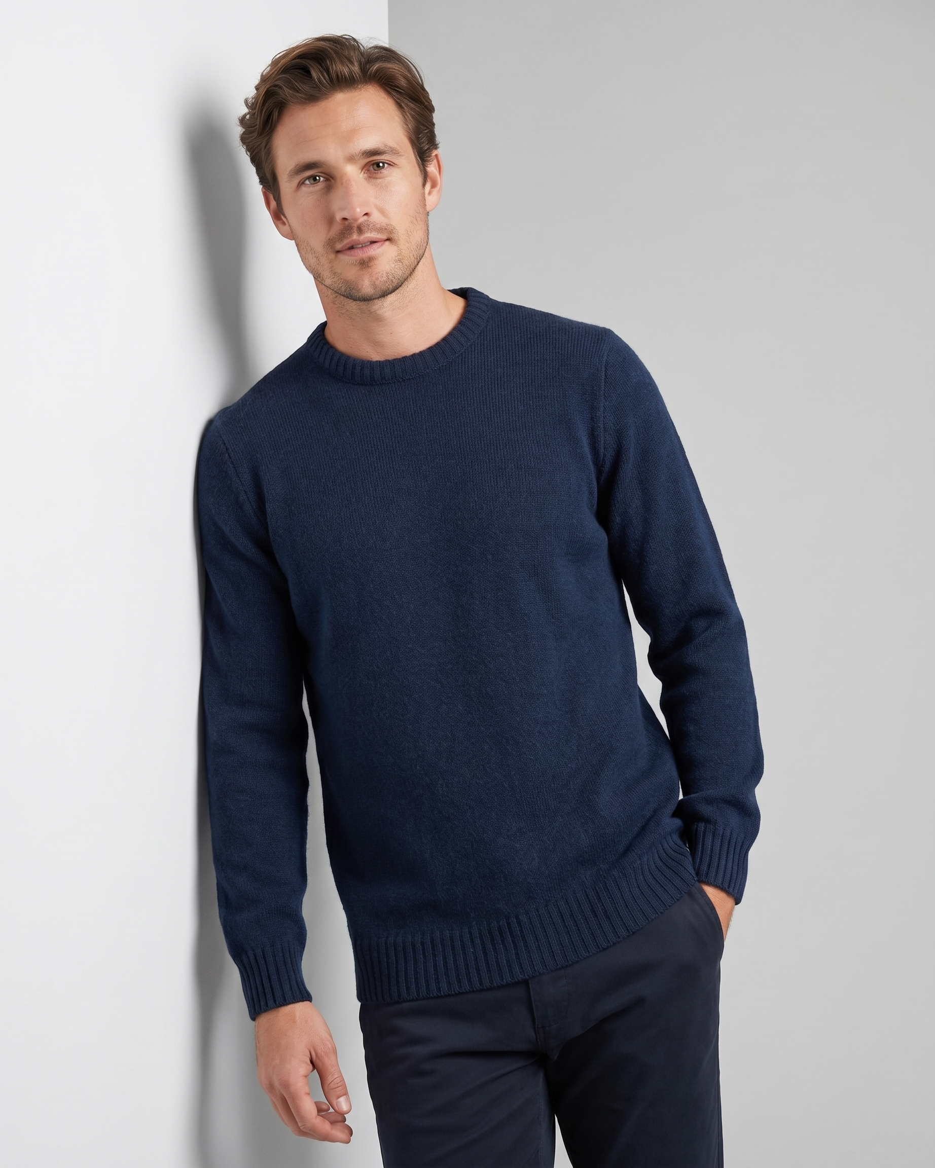 Man wearing a navy blue sweater against a light gray background