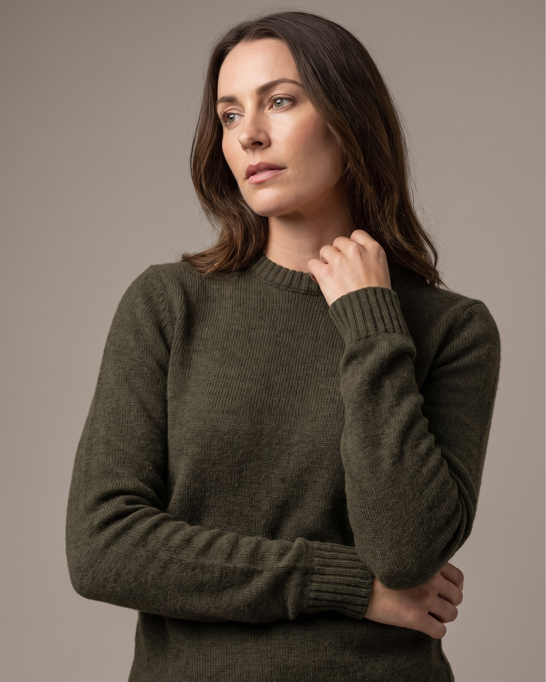 Woman wearing a olive green sweater against a neutral background