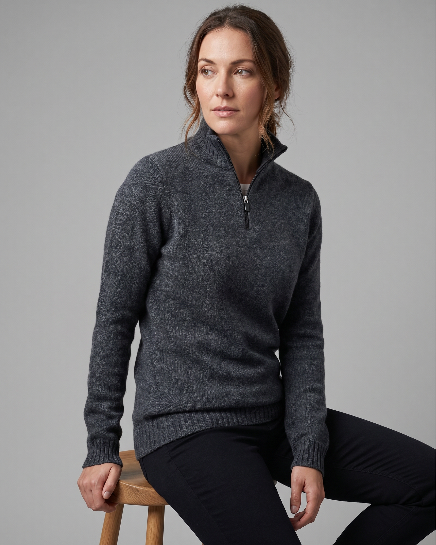 Woman wearing a gray sweater with a zipper on a gray background