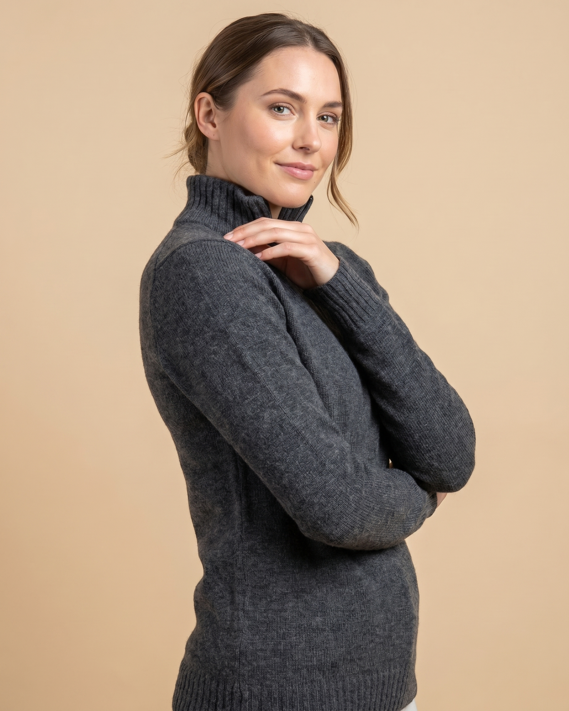 Woman wearing a dark gray sweater against a beige background