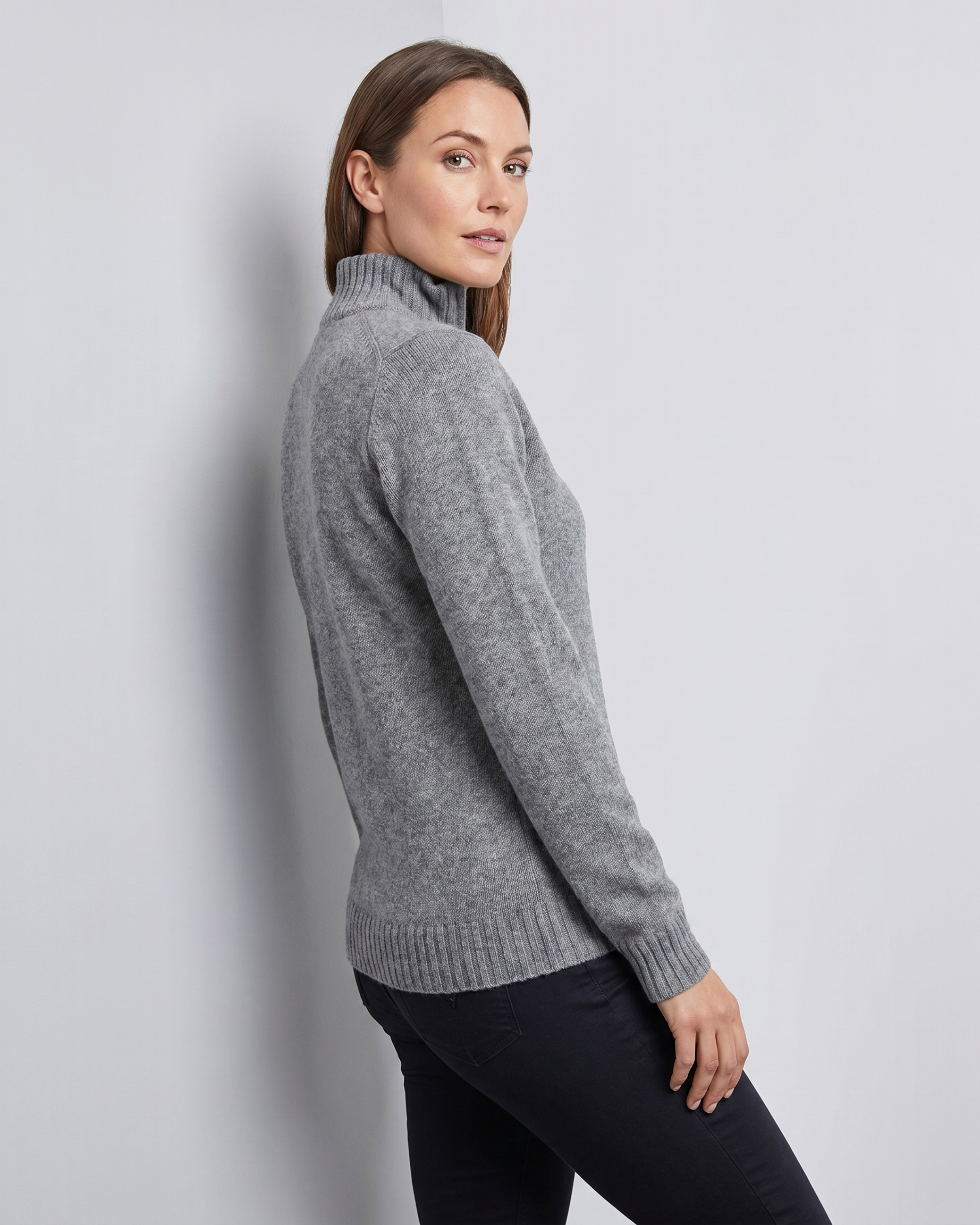 Woman wearing a gray quarter-zip sweater against a light gray background