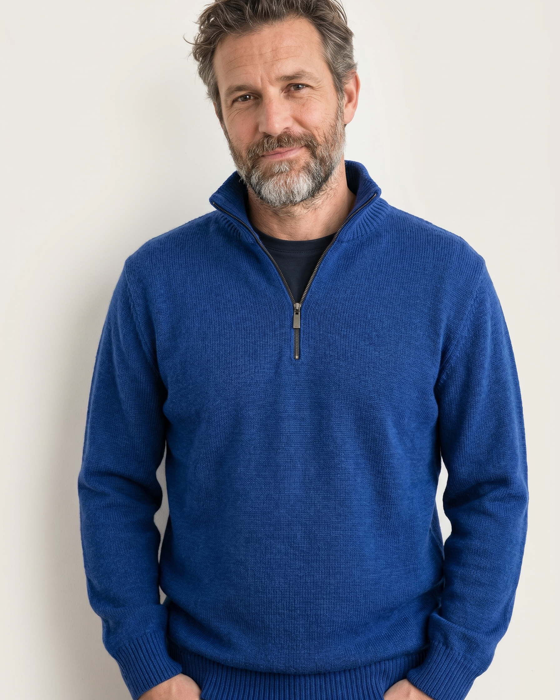 Man wearing a blue quarter-zip sweater against a plain background