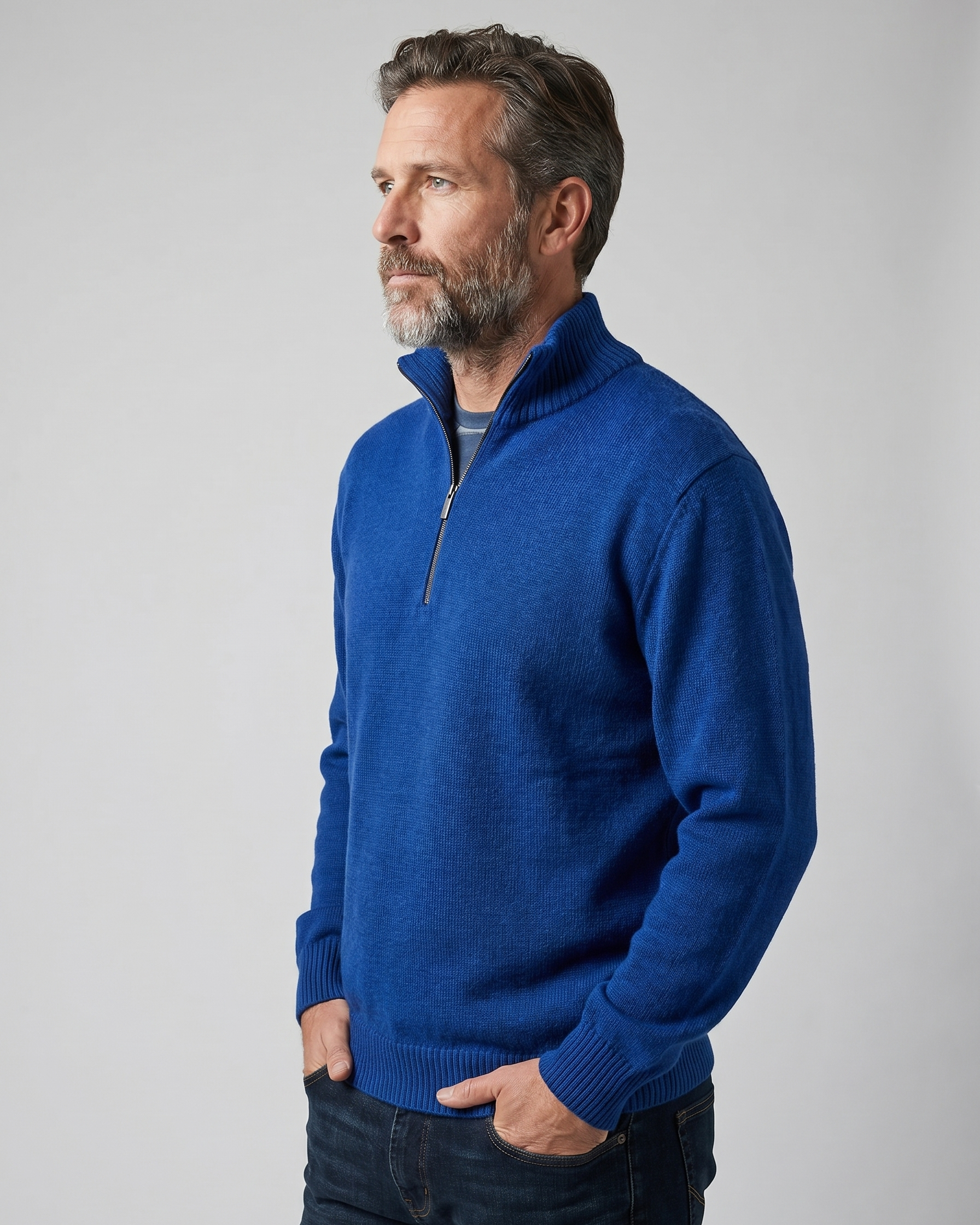Man wearing a blue quarter-zip sweater against a gray background