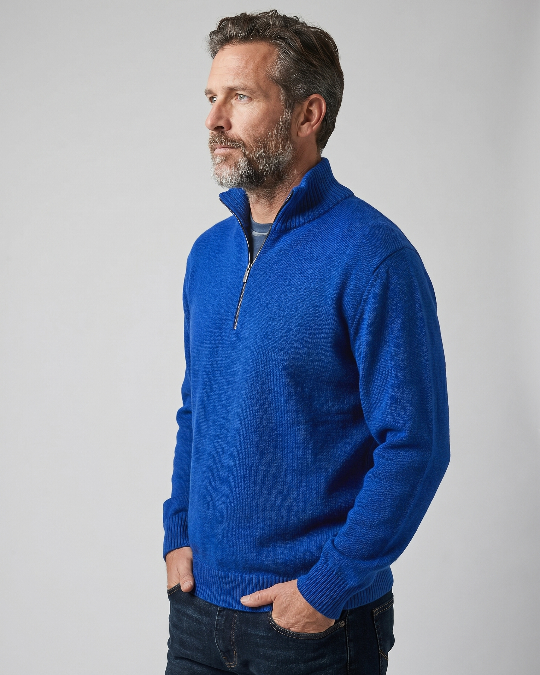 Man wearing a blue quarter-zip sweater against a gray background