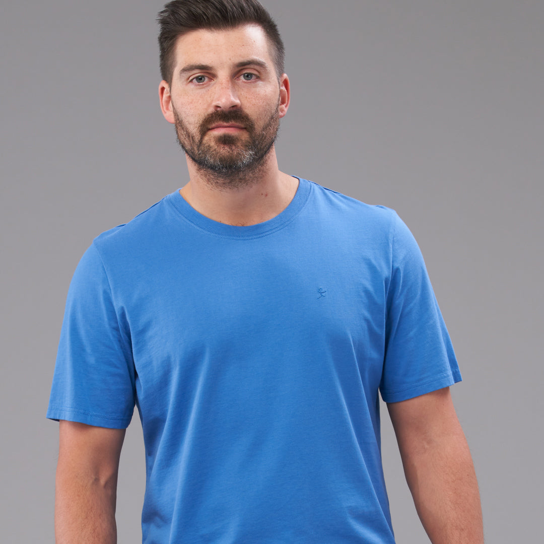 Dark haired man wearing a blue t-shirt.