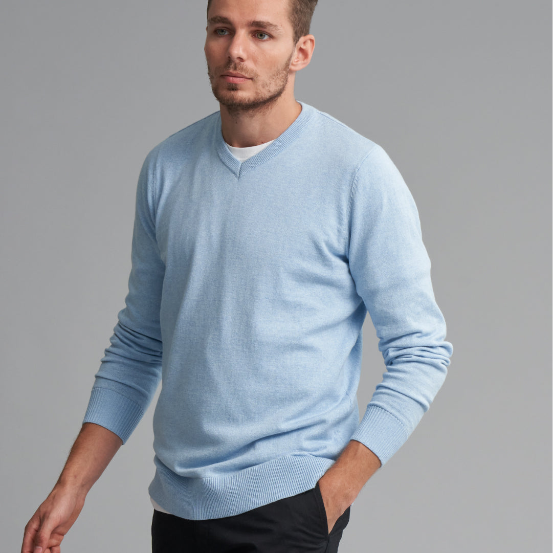 Brown haired man posing wearing a light blue sweater.