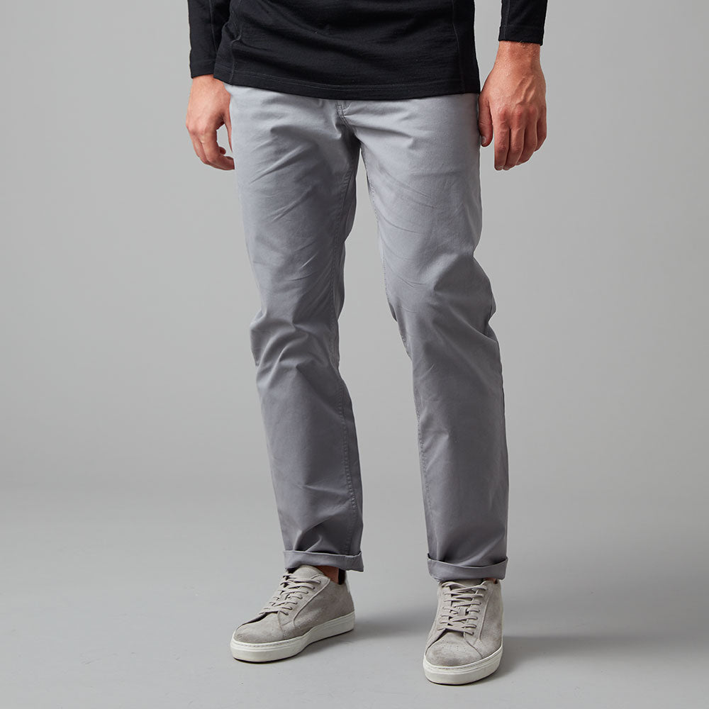 Man wearing a black long sleeve top and grey chino pants.