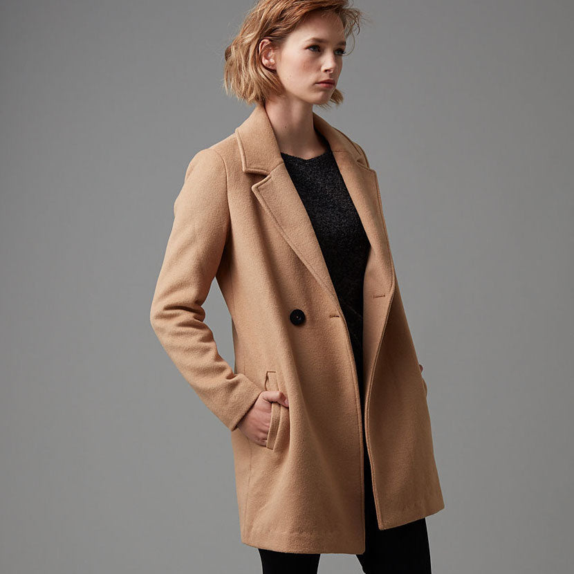 Blonde women wearing a long tan coloured jacket.