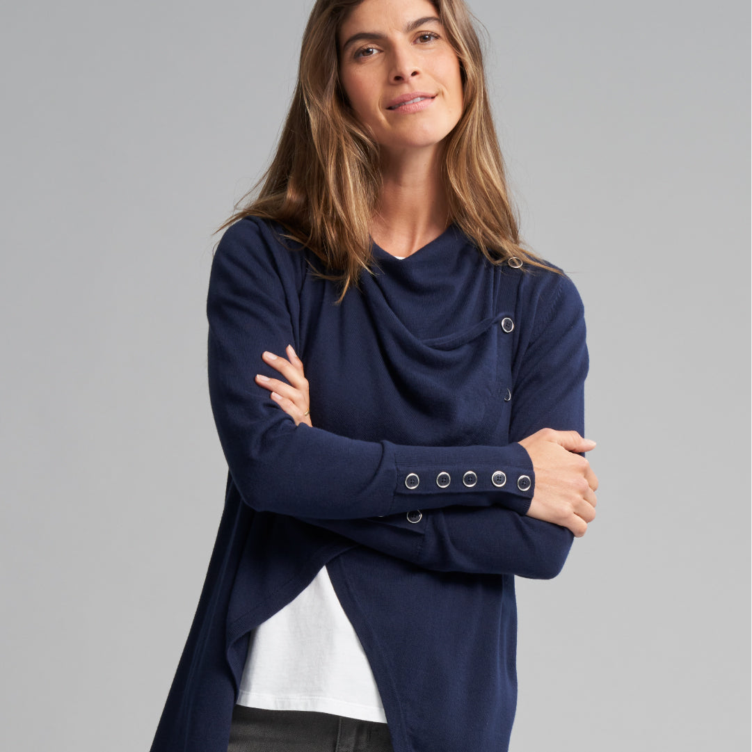 Brown haired women posing with arms crossed wearing a navy blue top.