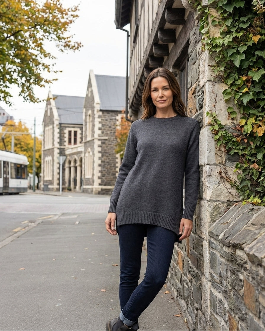 Brown haired women posing with arms crossed wearing a navy blue top.