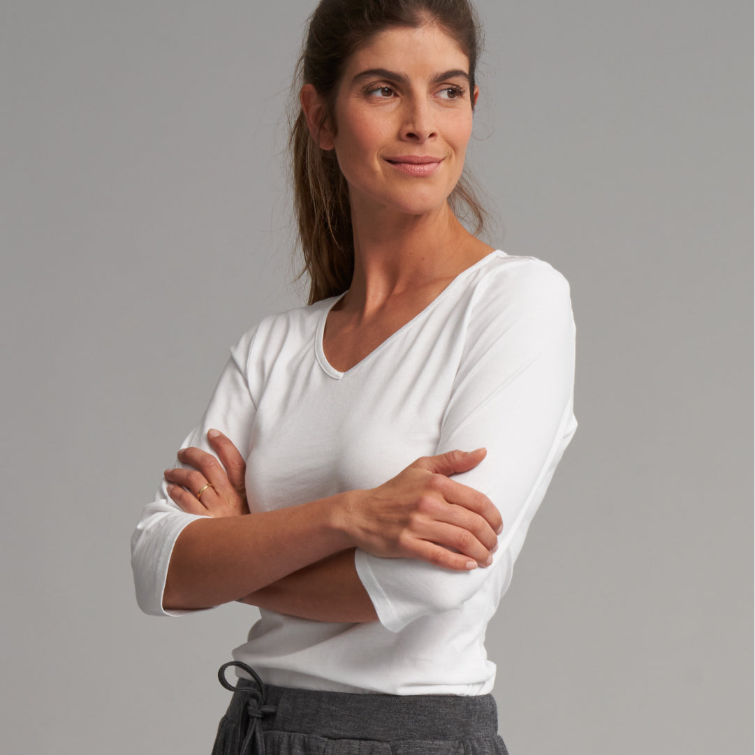 Dark haired women wearing white long sleeve top.