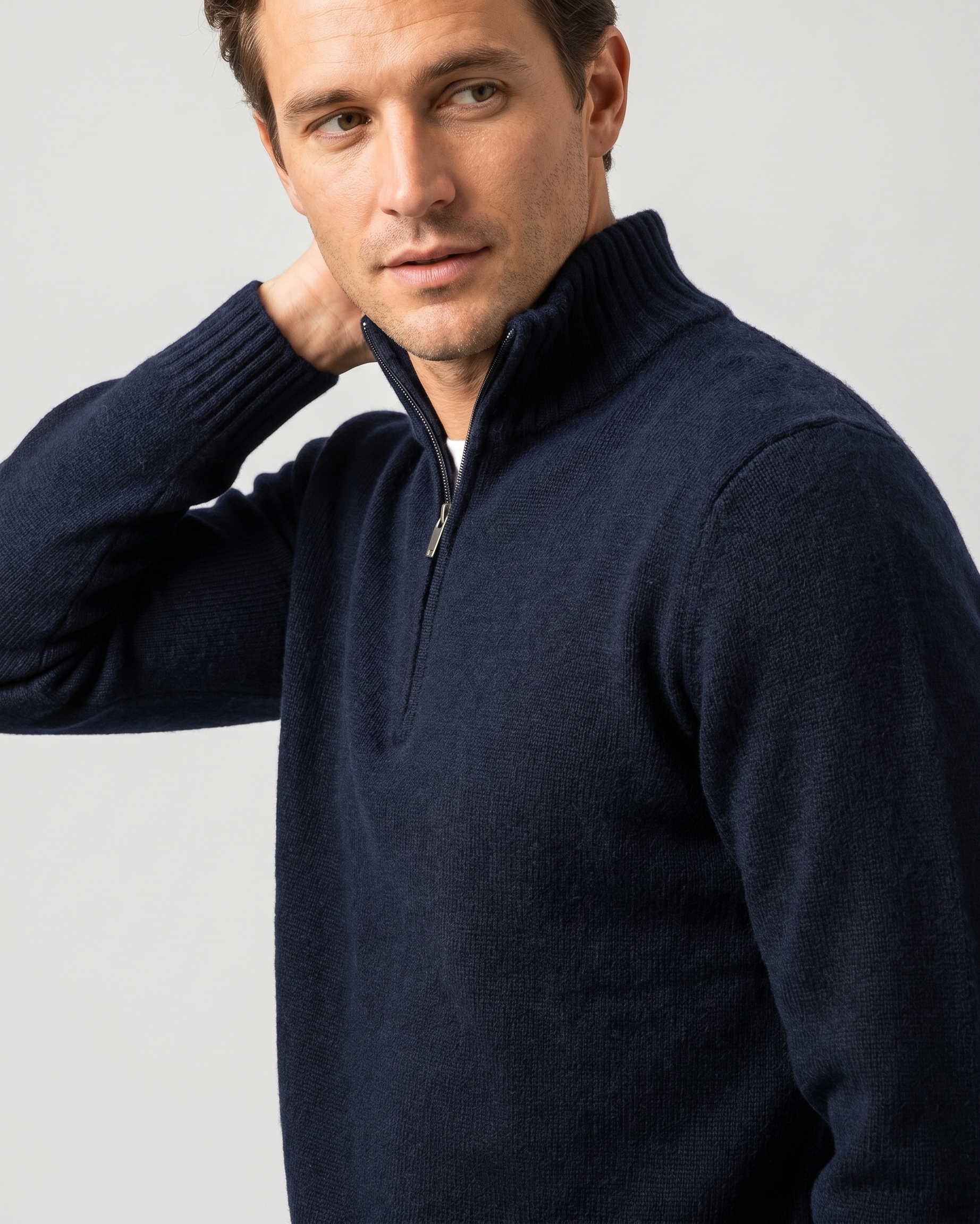 Man wearing a navy blue quarter-zip sweater against a light gray background
