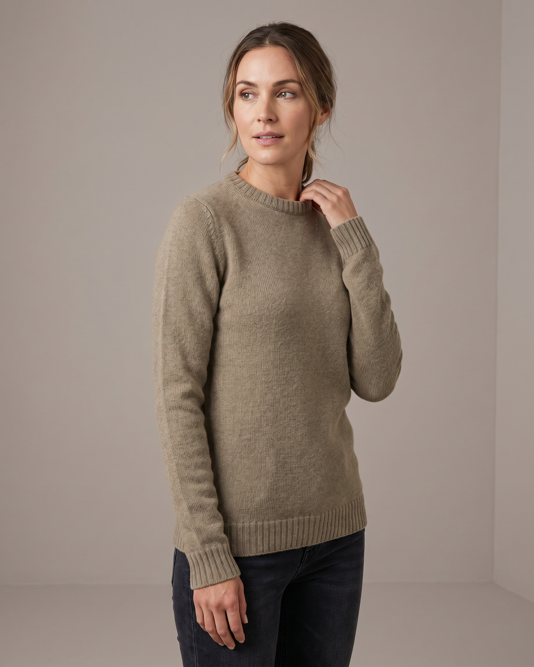 Woman wearing a beige sweater against a plain background
