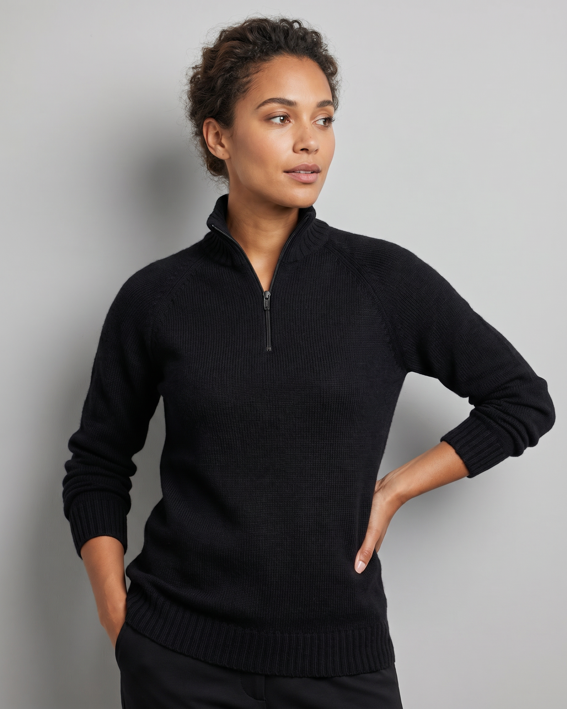 Woman wearing a black quarter-zip sweater against a gray background
