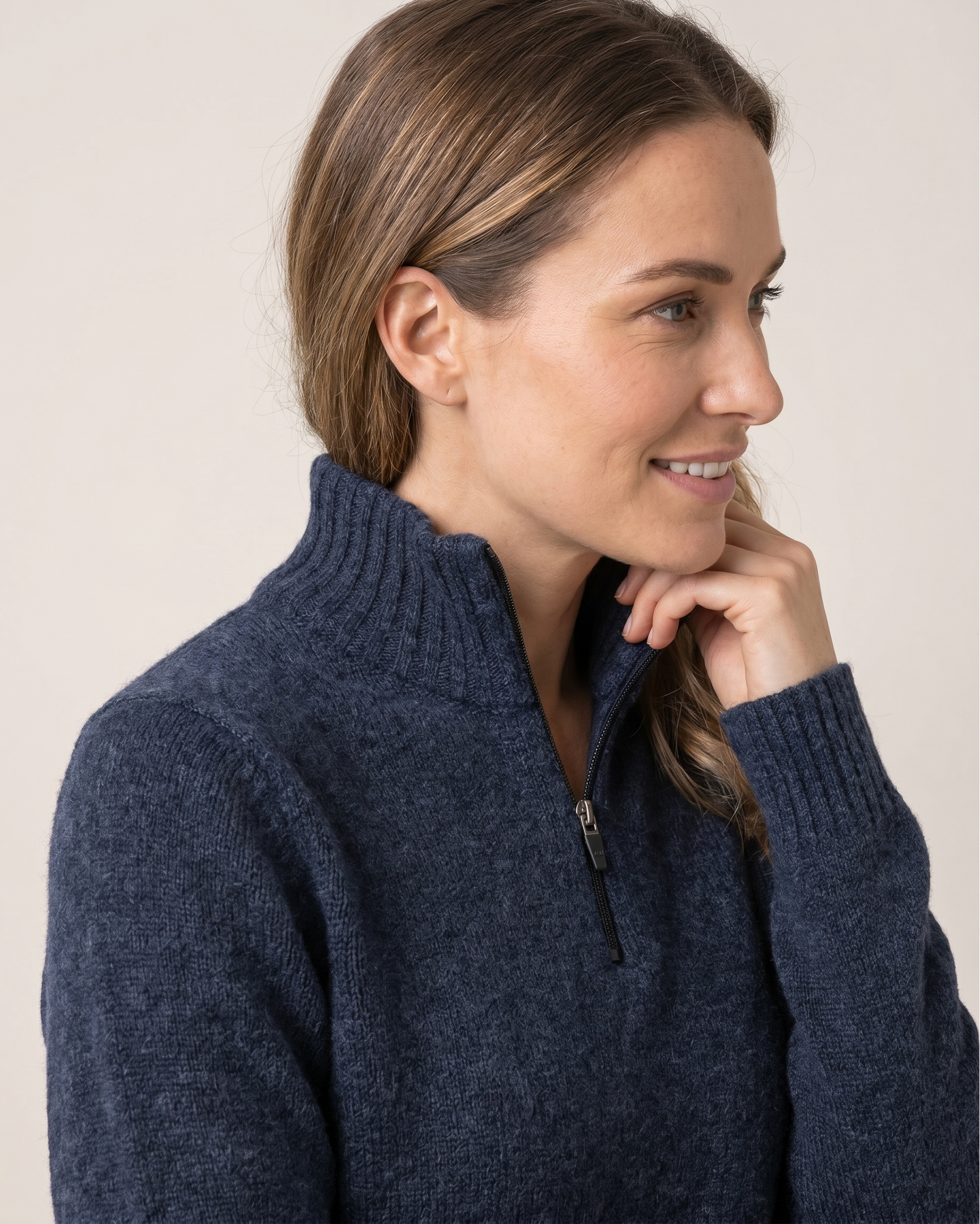 Woman wearing a navy handel sweater against a plain background