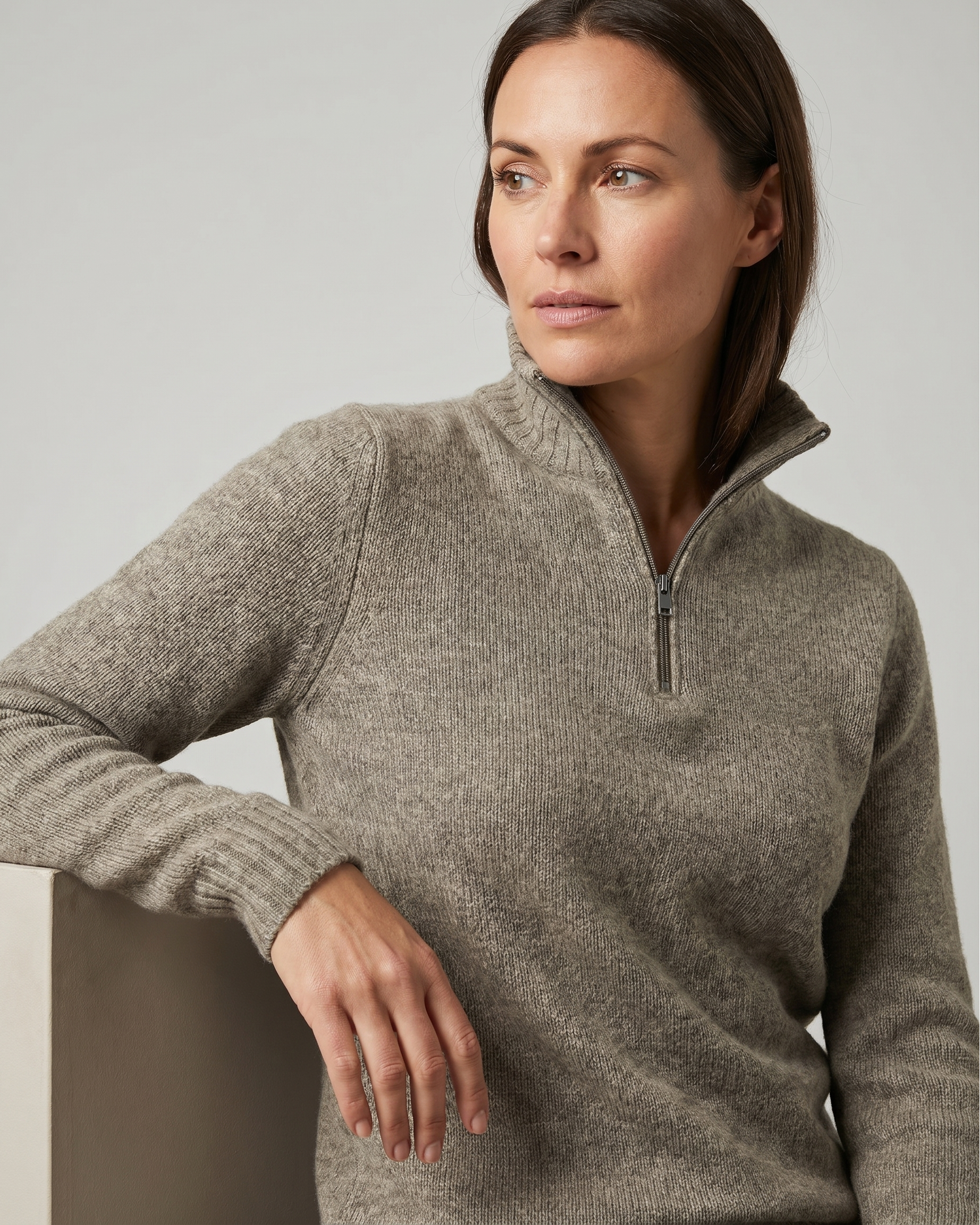 Woman wearing a oatmeal sweater with a quarter zip on a light gray background