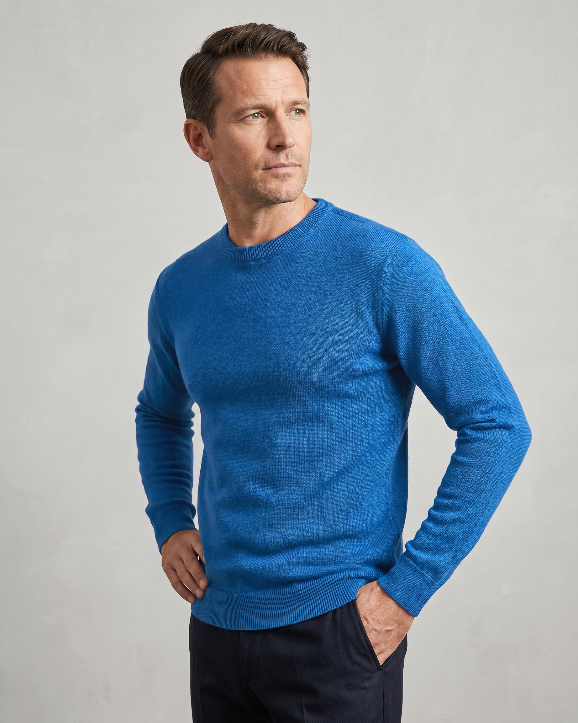 Man wearing a blue sweater against a gray background