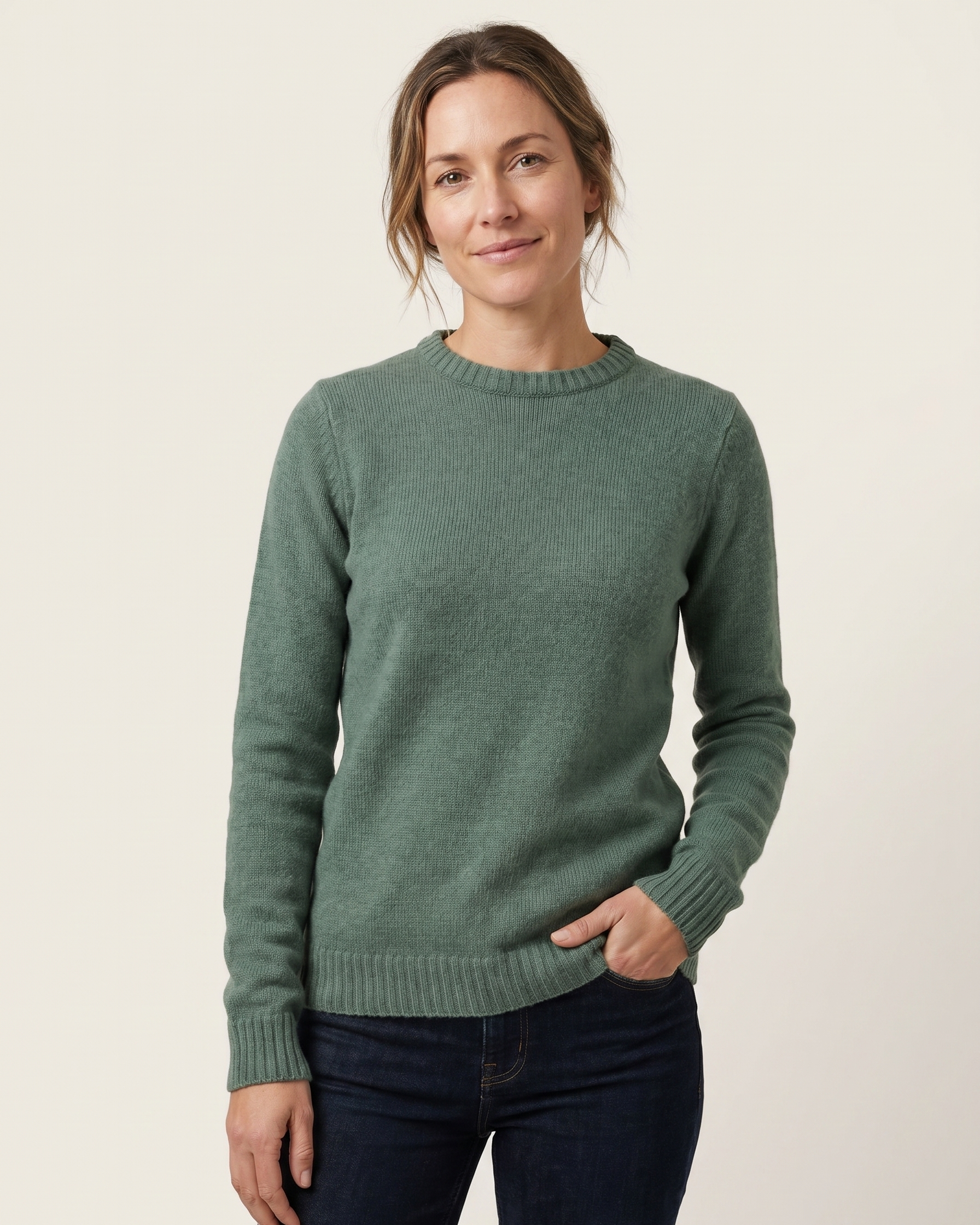 Woman wearing a sage sweater against a beige background